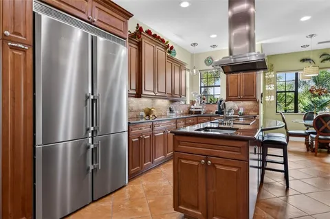 a kitchen with stainless steel appliances granite countertop a stove a sink dishwasher and a refrigerator with wooden cabinets