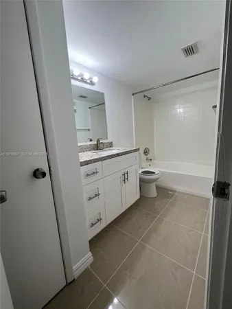 a spacious bathroom with a double vanity sink a toilet and a mirror