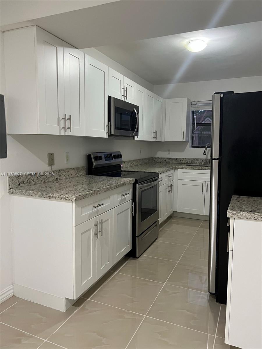 15581 Southwest 104th Terrace, Unit 224 Miami, FL 33196 - Photo 8 of 18 a kitchen with a sink stove and white cabinets