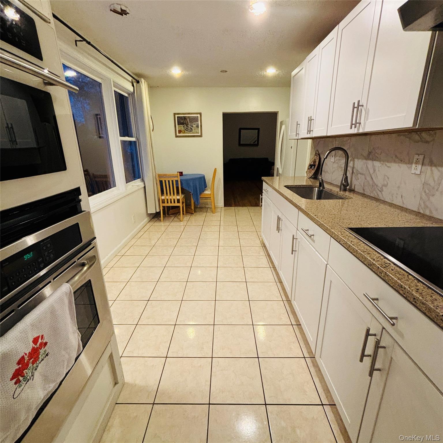 929 Fox Meadow Road Yorktown Heights, NY 10598 - Photo 23 of 39 Kitchen with white cabinets, light tile patterned floors, light stone countertops, backsplash, and stainless steel (double oven- not included)