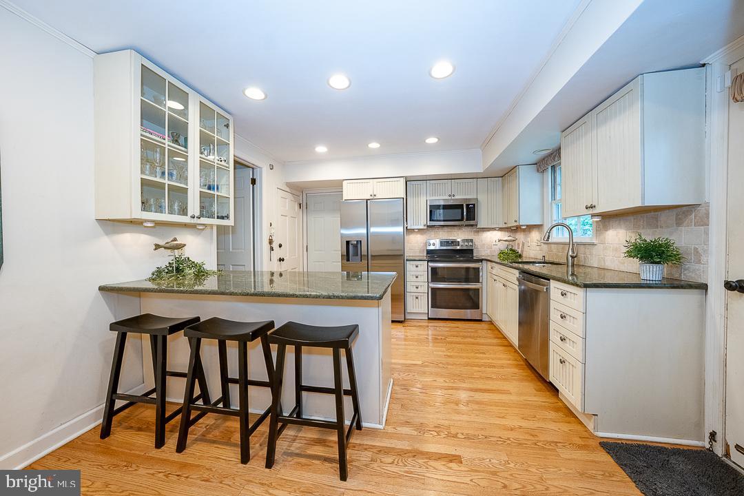 749 Mancill Road Wayne, PA 19087 - Photo 9 of 34 a kitchen with stainless steel appliances granite countertop a stove top oven a sink dishwasher and white cabinets with wooden floor