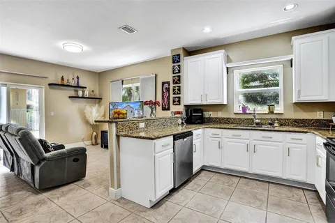 a kitchen with granite countertop cabinets a sink a window and stainless steel appliances