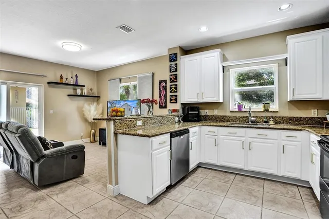 a kitchen with granite countertop cabinets a sink a window and stainless steel appliances