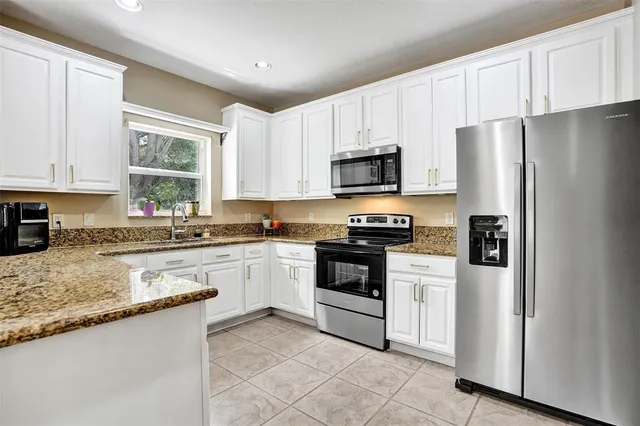 a kitchen with granite countertop white cabinets and white stainless steel appliances