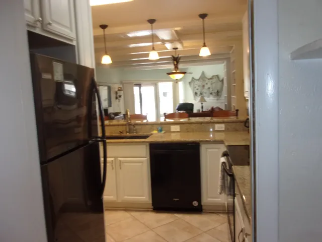 a kitchen with kitchen island granite countertop a sink a counter top space and living room area