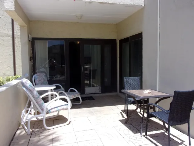 a balcony with table and chairs potted plants