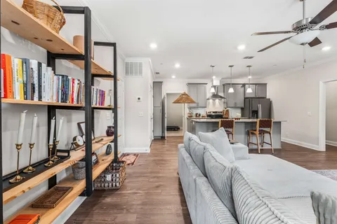 a living room with furniture kitchen view and a large window