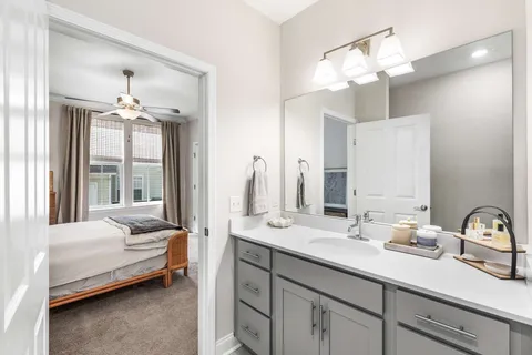 a en suite bathroom with a double vanity sink large mirror and chandelier