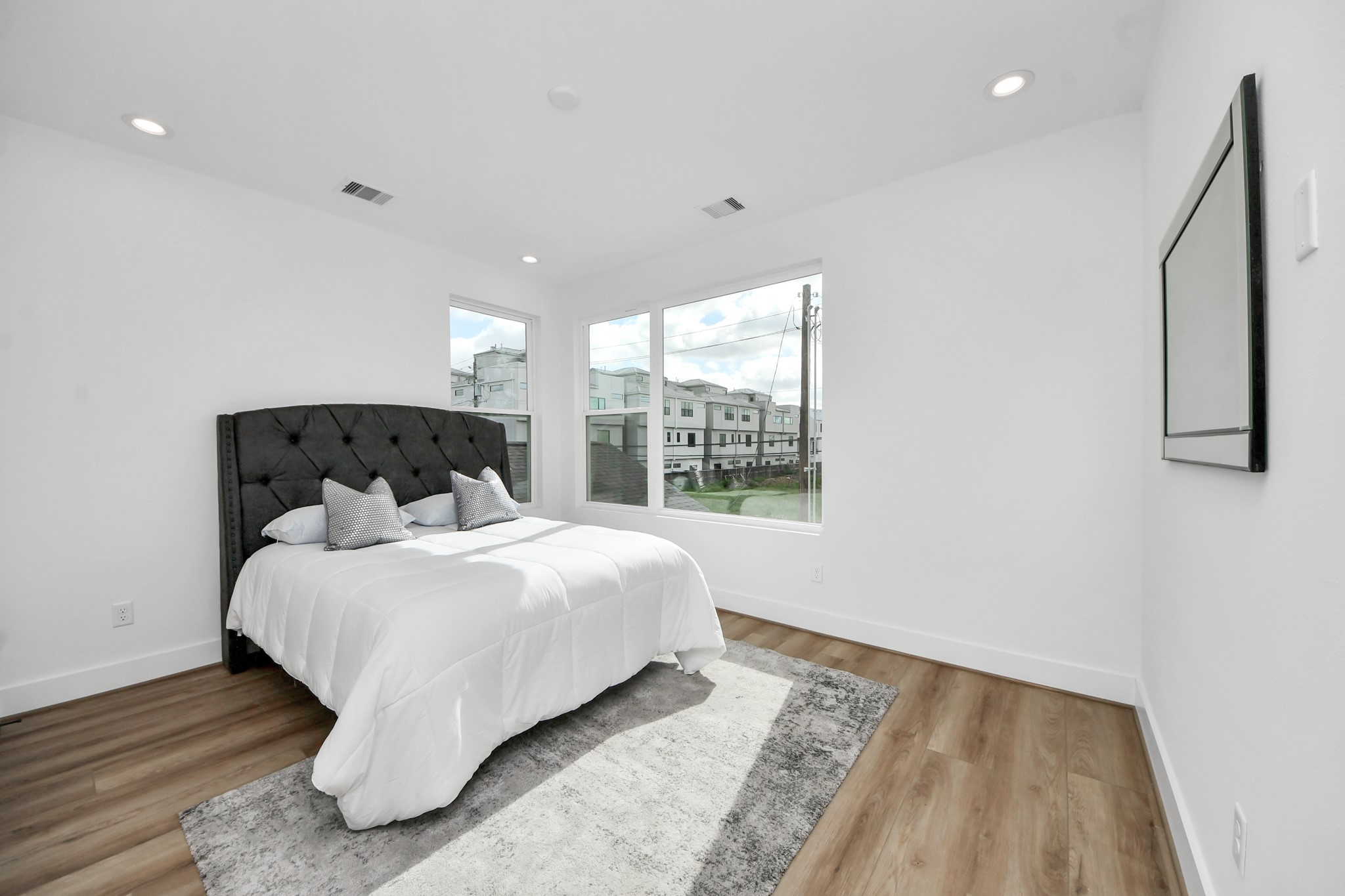507 Middle Street Houston, TX 77003 - Photo 32 of 48 Discover the inviting second-floor bedroom, awash with natural light from expansive windows and featuring elegant wood flooring for a serene retreat.