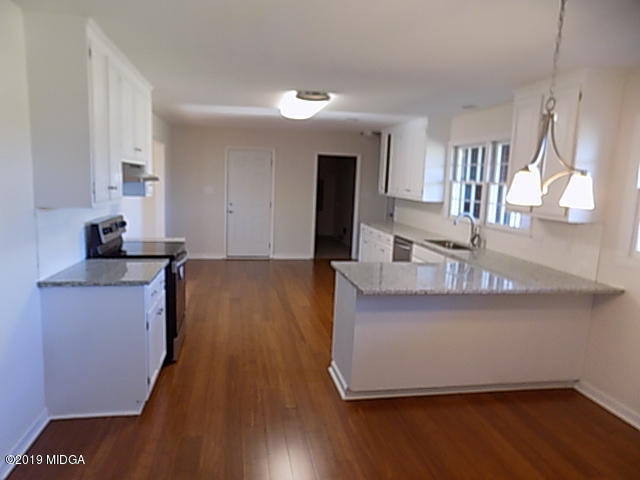 7940 Bethel Church Road Lizella, GA 31052 - Photo 8 of 34 a kitchen with kitchen island granite countertop a sink cabinets and wooden floor