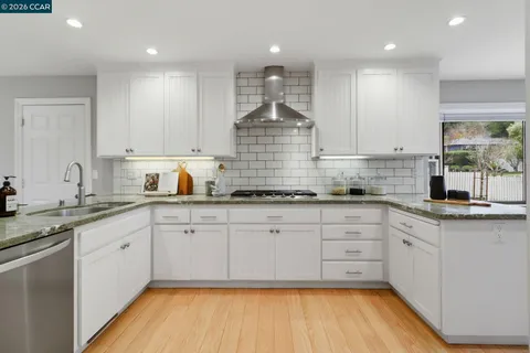 a kitchen with white cabinets and sink