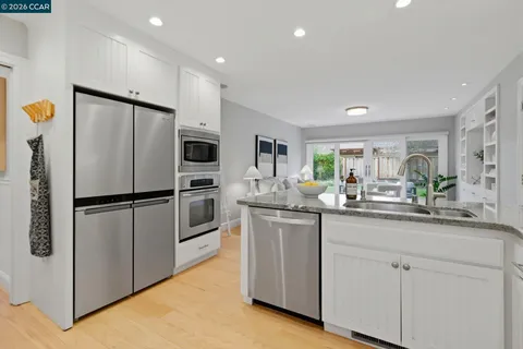 a kitchen with stainless steel appliances granite countertop wooden cabinets a sink and a refrigerator
