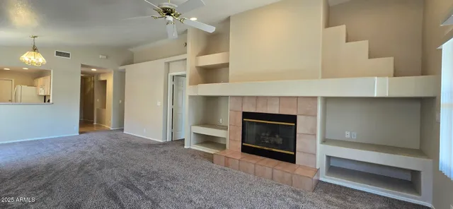 a view of an empty room with a fireplace and a fan