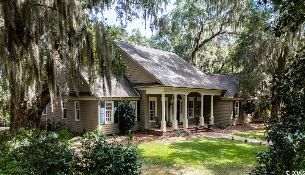 762 Wraggs Ferry Road Georgetown, SC 29440 - Photo 6 of 33 Rear view of property featuring a porch, roof with shingles, and a lawn