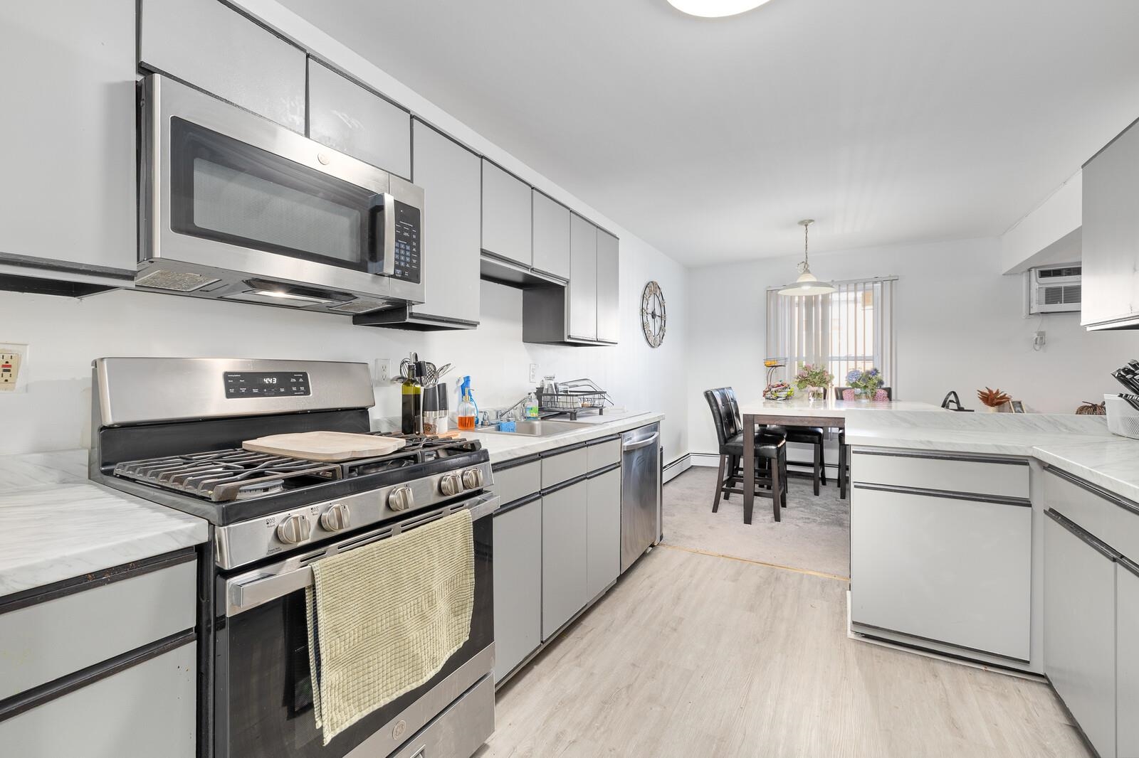 a kitchen with stainless steel appliances a stove a sink dishwasher a microwave oven with cabinets and wooden floor