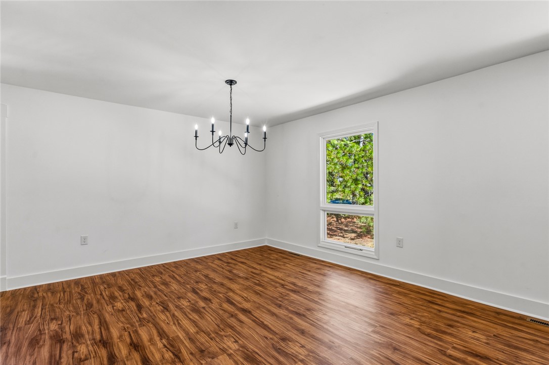 208 Williamsburg Road Anderson, SC 29621 - Photo 8 of 48 Rich wood flooring pairs elegantly with a classic wrought-iron chandelier and backyard window views.