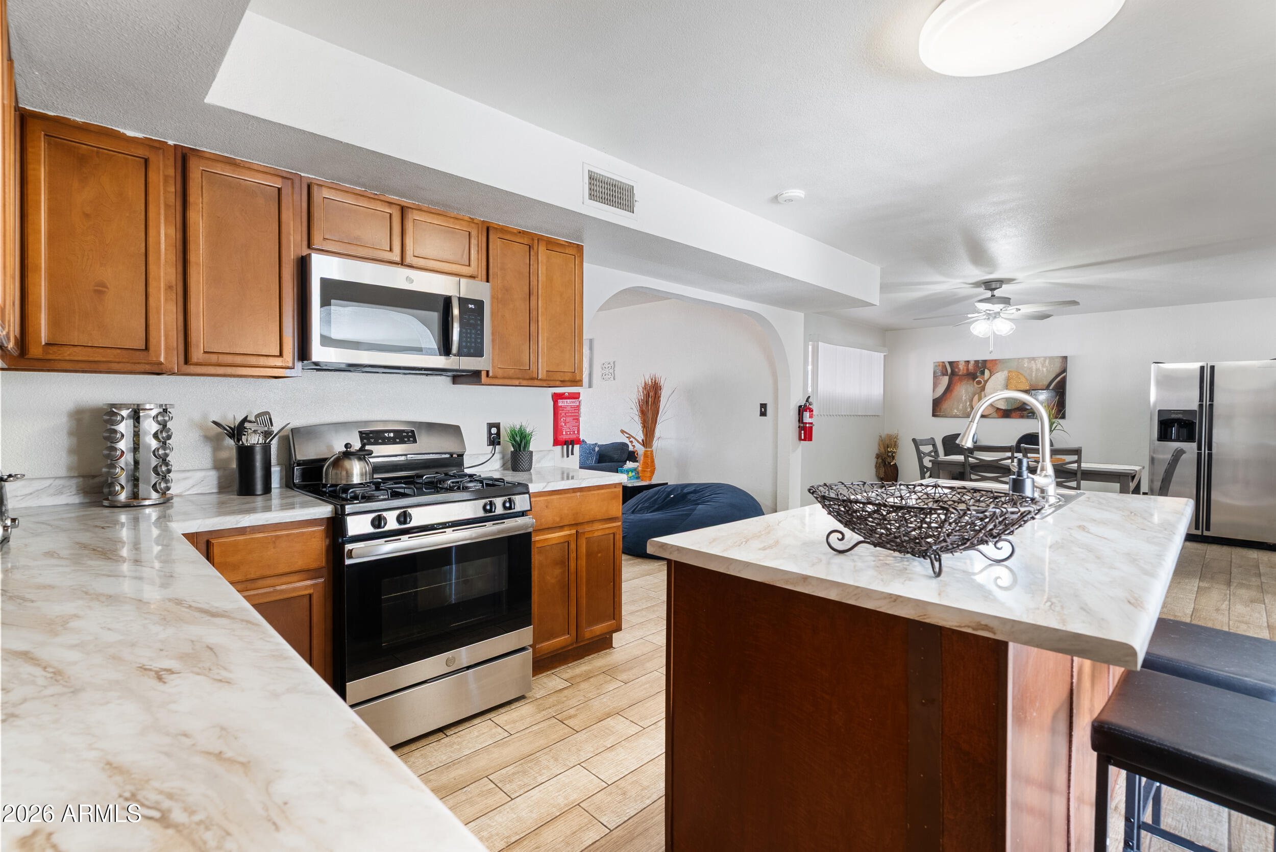 3631 West Colter Street Phoenix, AZ 85019 - Photo 12 of 45 a kitchen with stainless steel appliances granite countertop a stove top oven a sink dishwasher a dining table and chairs with wooden cabinets