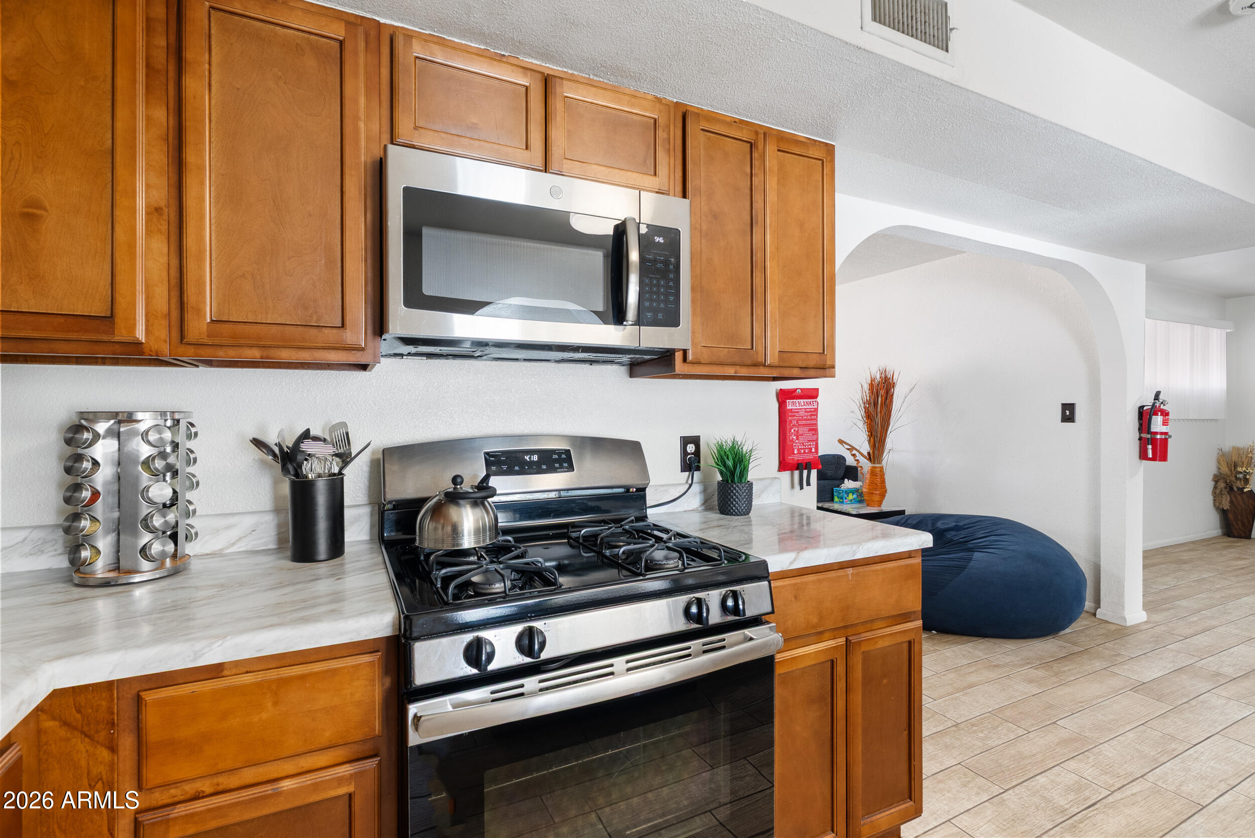 3631 West Colter Street Phoenix, AZ 85019 - Photo 13 of 45 a kitchen with stainless steel appliances a stove a microwave a sink and cabinets