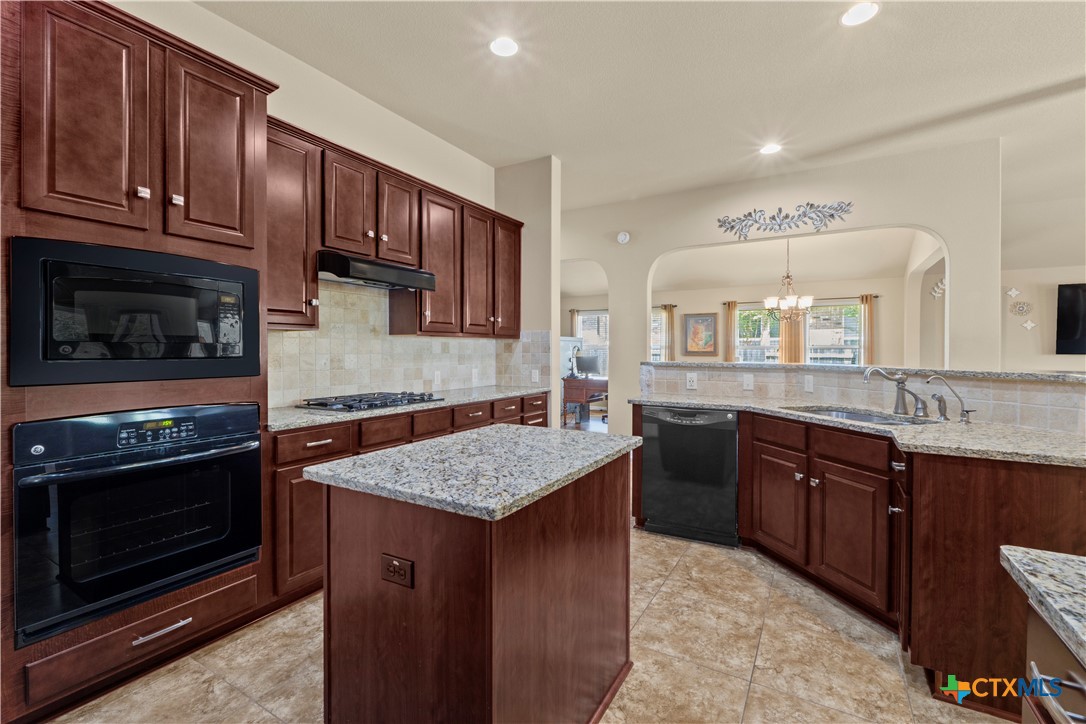 20525 Jackies Ranch Boulevard Pflugerville, TX 78660 - Photo 2 of 30 Kitchen featuring built in appliances, a center island, decorative backsplash