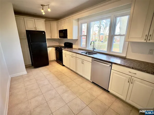 a kitchen with granite countertop a sink stove and cabinets