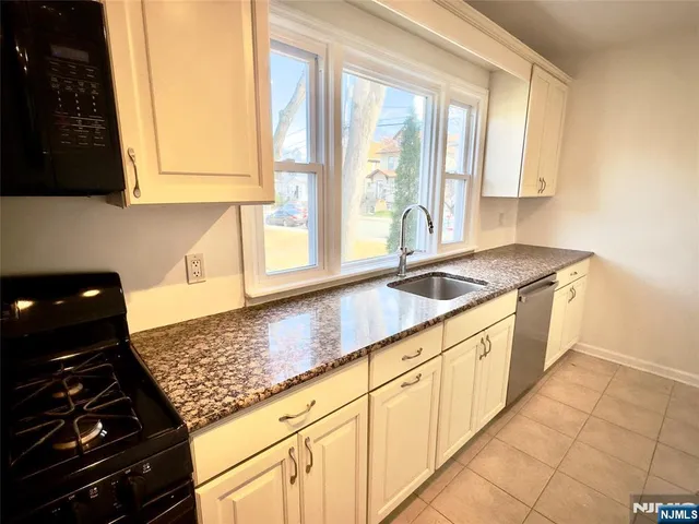 a kitchen with granite countertop a sink stove and cabinets