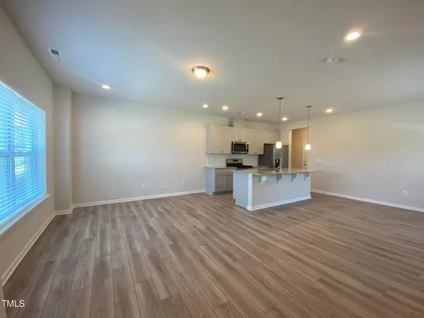 a view of kitchen with kitchen island wooden floor and living room