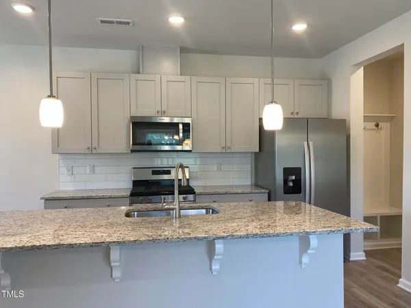 a kitchen with stainless steel appliances granite countertop a sink a refrigerator and a granite counter tops