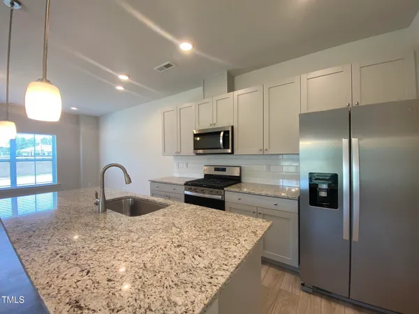 a kitchen with kitchen island granite countertop a sink stainless steel appliances and cabinets