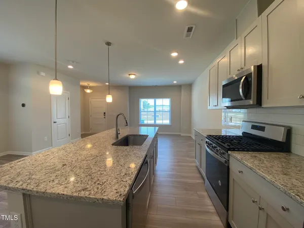 a kitchen with kitchen island granite countertop a stove and a sink