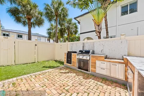 a backyard of a house with wooden fence and palm trees