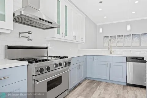 a white kitchen with stainless steel appliances granite countertop a sink and cabinets