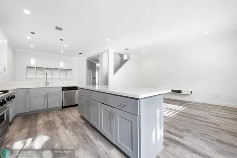 a large white kitchen with a sink a counter top space and stainless steel appliances
