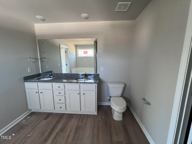 a bathroom with a granite countertop sink toilet and mirror