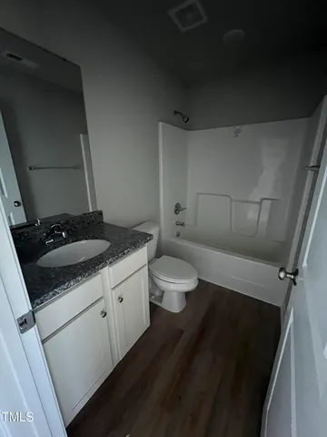 a bathroom with a granite countertop sink and a toilet