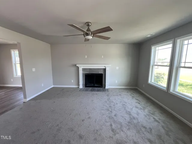 an empty room with windows and fireplace