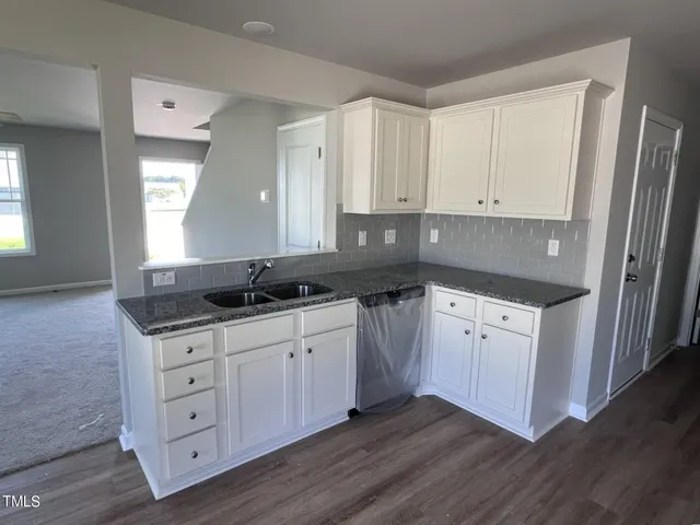 a kitchen with granite countertop white cabinets and sink