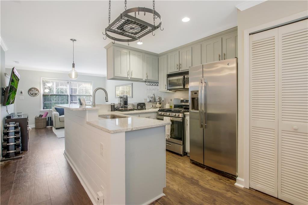 a kitchen with kitchen island a counter top space a sink stainless steel appliances and cabinets