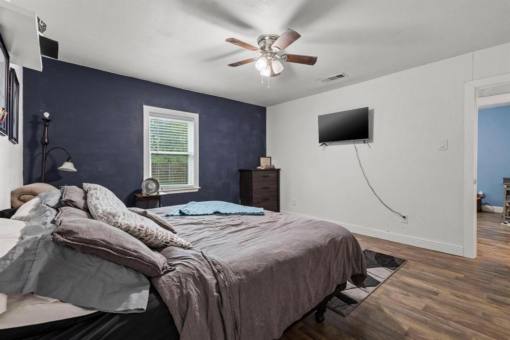 221 Braz Street Bonham, TX 75418 - Photo 19 of 26 a bedroom with a bed a flat screen tv and a chandelier
