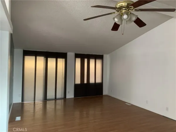 an empty room with chandelier fan and windows