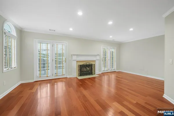 a view of an empty room with wooden floor fireplace and a window