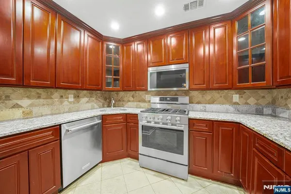 a kitchen with stainless steel appliances granite countertop a refrigerator stove top oven and sink