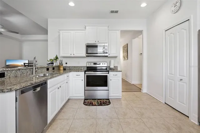 a kitchen with granite countertop a refrigerator and a stove top oven