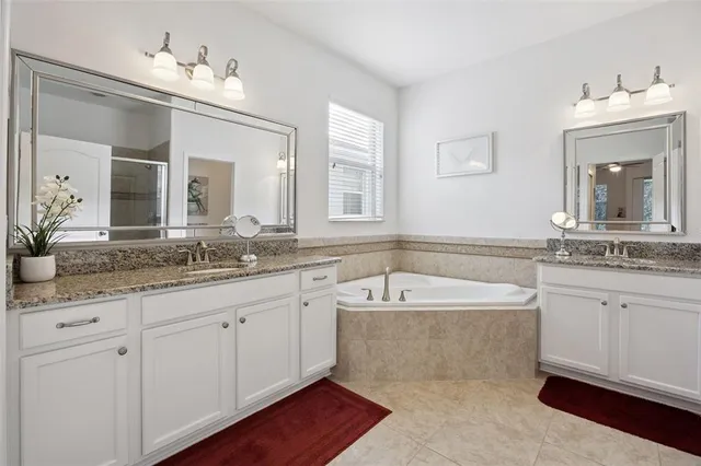 a spacious bathroom with a granite countertop tub double sink and a mirror