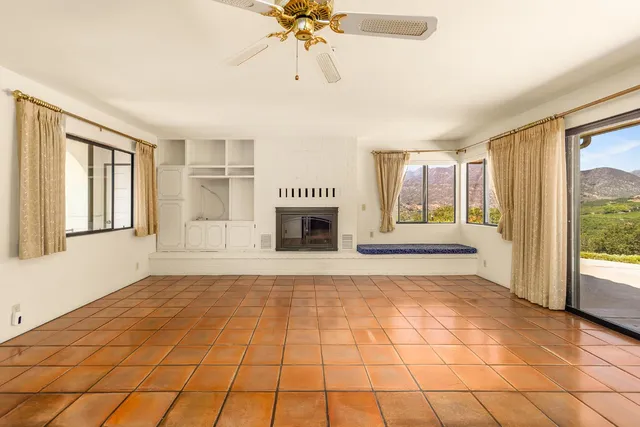 a view of an empty room with window and chandelier fan