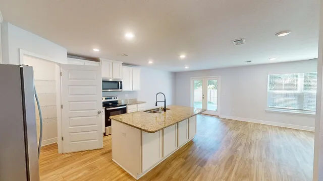 a kitchen with granite countertop a stove a sink and a microwave
