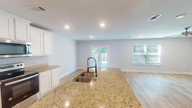a kitchen with kitchen island granite countertop a sink a counter top space stainless steel appliances and cabinets