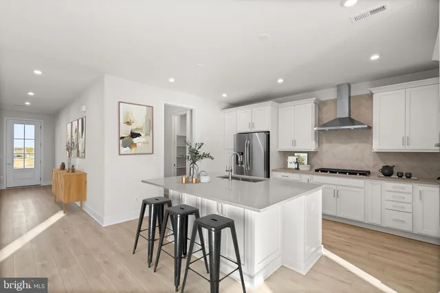 a kitchen with stainless steel appliances granite countertop a stove a sink a refrigerator a dining table and chairs