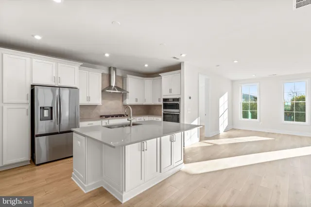 a kitchen with stainless steel appliances granite countertop a refrigerator sink and white cabinets