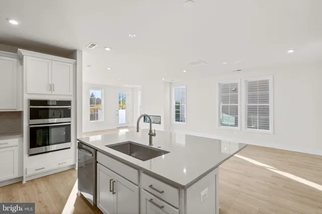 a kitchen with stainless steel appliances granite countertop a sink a stove and a microwave oven with wooden floor