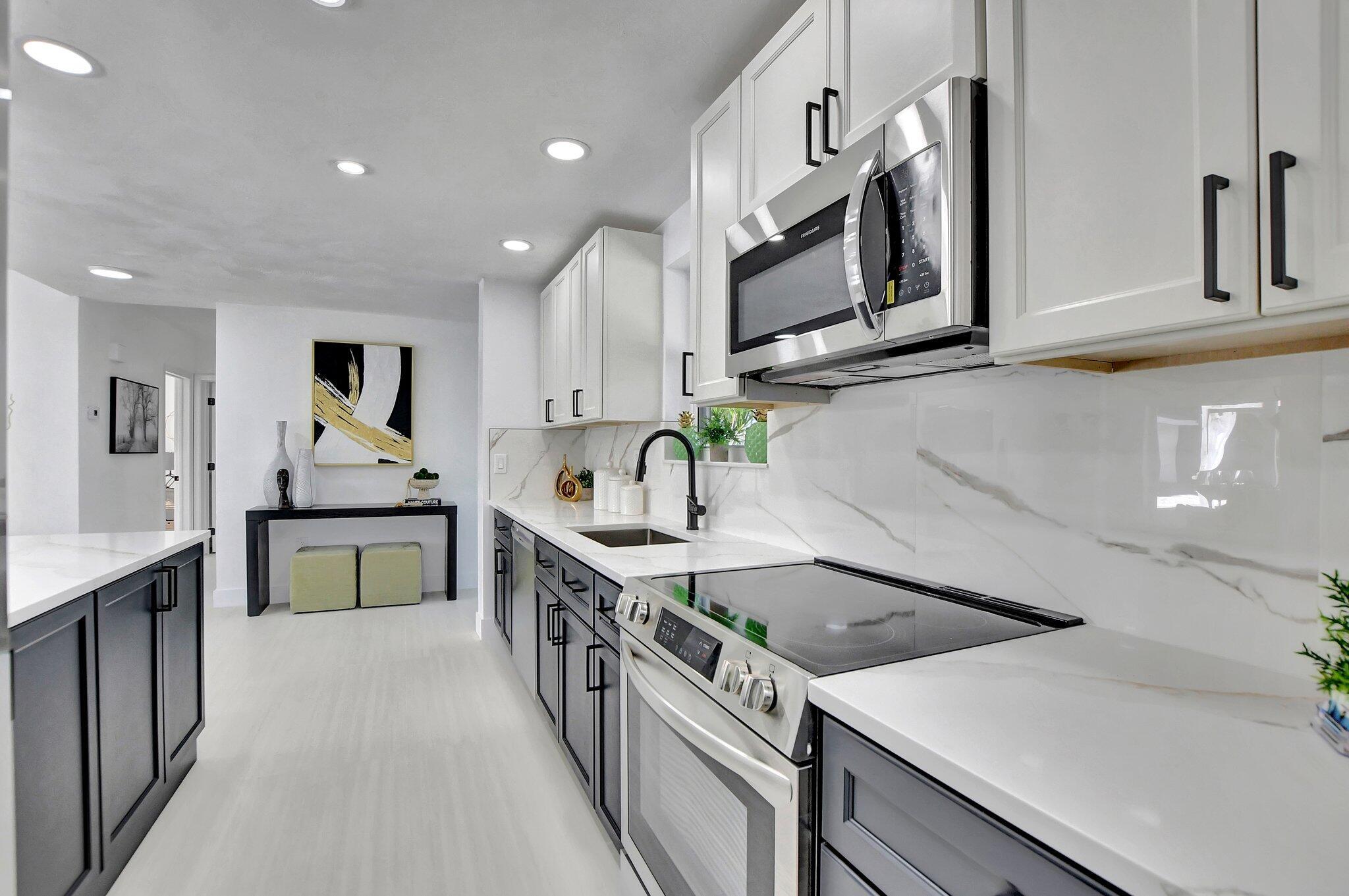 832 Southwest 10th Avenue Boca Raton, FL 33486 - Photo 8 of 57 a kitchen with stainless steel appliances granite countertop a sink and stove top oven